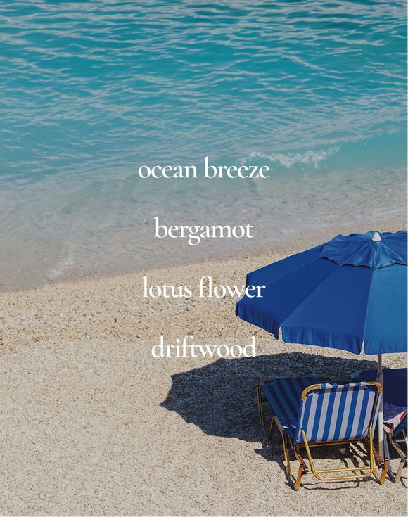 Scent notes: ocean breeze, bergamot, lotus flower, driftwood over beach chairs and blue umbrella