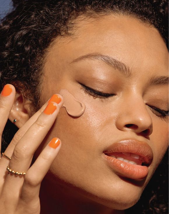 Model applying Beyond Glow Tinted Mineral Sunscreen to face