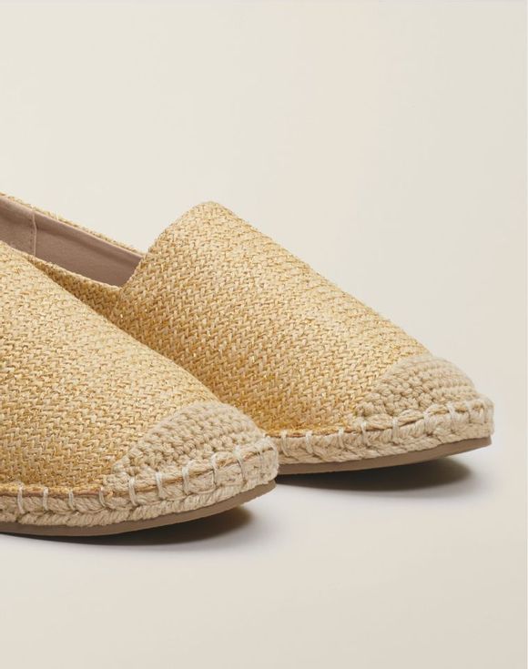 Model wearing gold espadrilles with blue cropped jeans