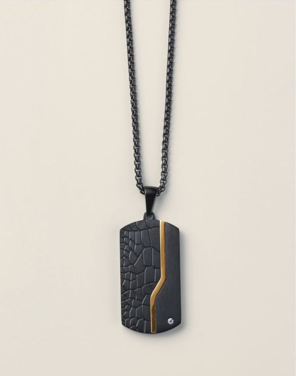 Close-up angled view of black croc-texture dog tag pendant with gold-tone stripe and crystal accent